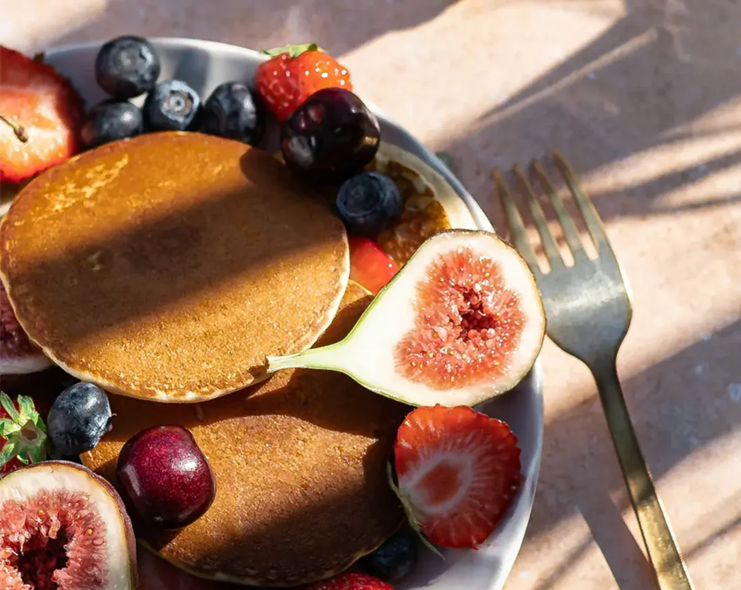 Assiette de pancakes gourmands accompagnés de figues fraîches, fraises, cerises et myrtilles pour le brunch de la Fête des Mères à l'Abbaye des Capucins.